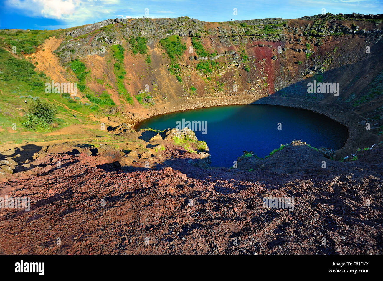 Kerid volcanic crater lake Grimsnes area of Iceland Unrecognizable people along caldera and climbing give sense of scale HDR Stock Photo