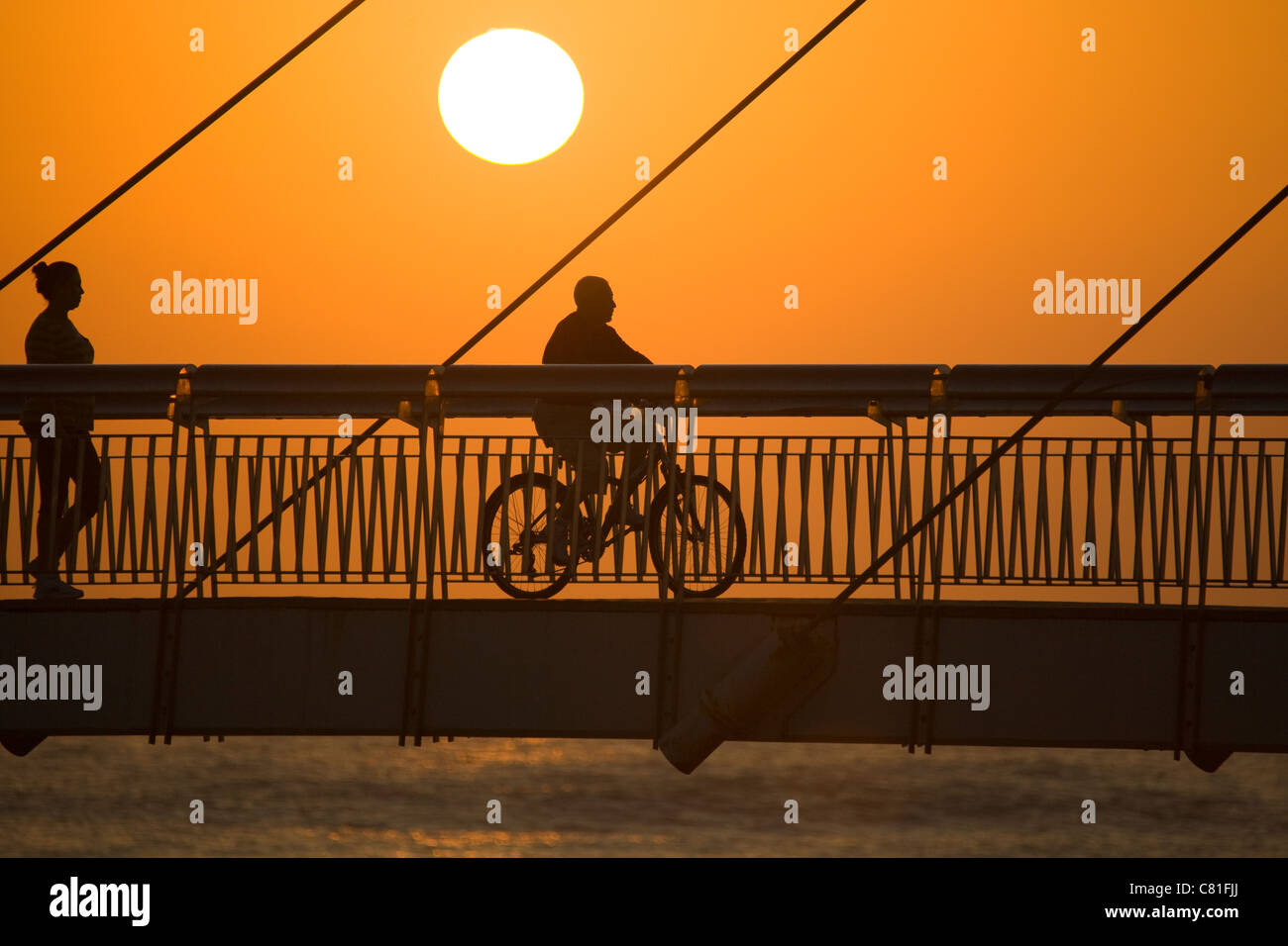 Silhouettes of people crossing a suspension bridge in Spain Stock Photo ...