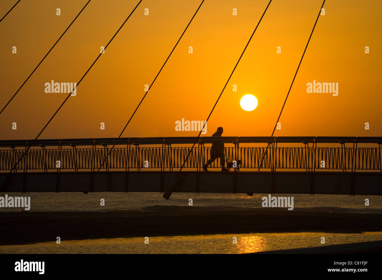 Silhouettes of people crossing a suspension bridge in Spain Stock Photo ...