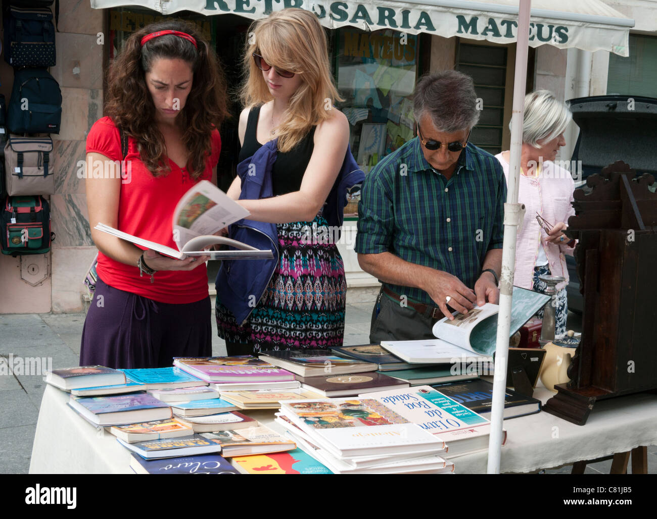 People inspecting books at a flea market, held on the last Saturday of the month, in Praça do Comércio, Coimbra, Portugal. Stock Photo