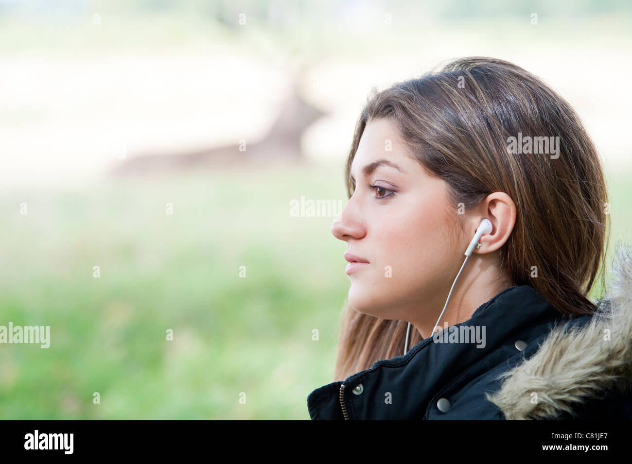 15 Year old girl listening to music on a music player with headphones in the park. Stock Photo