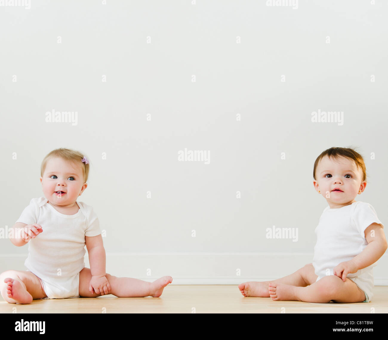 Babies sitting on floor Stock Photo