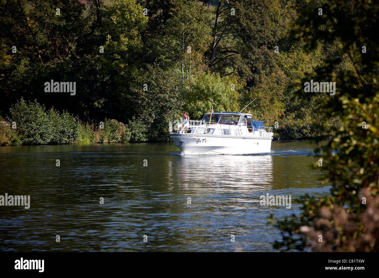 A lady on the deck of a cruiser on the River Thames between Pangbourne and Maple Durham, Berkshire. Stock Photo