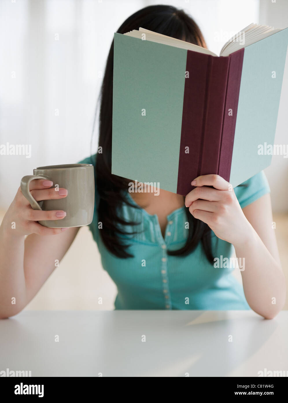 Korean woman drinking coffee and reading book Stock Photo