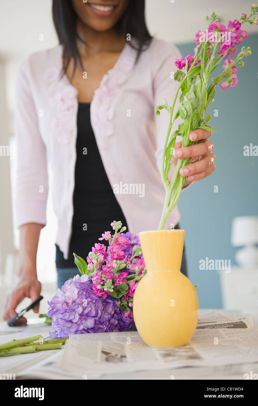 African American woman arranging flowers in base Stock Photo - Alamy