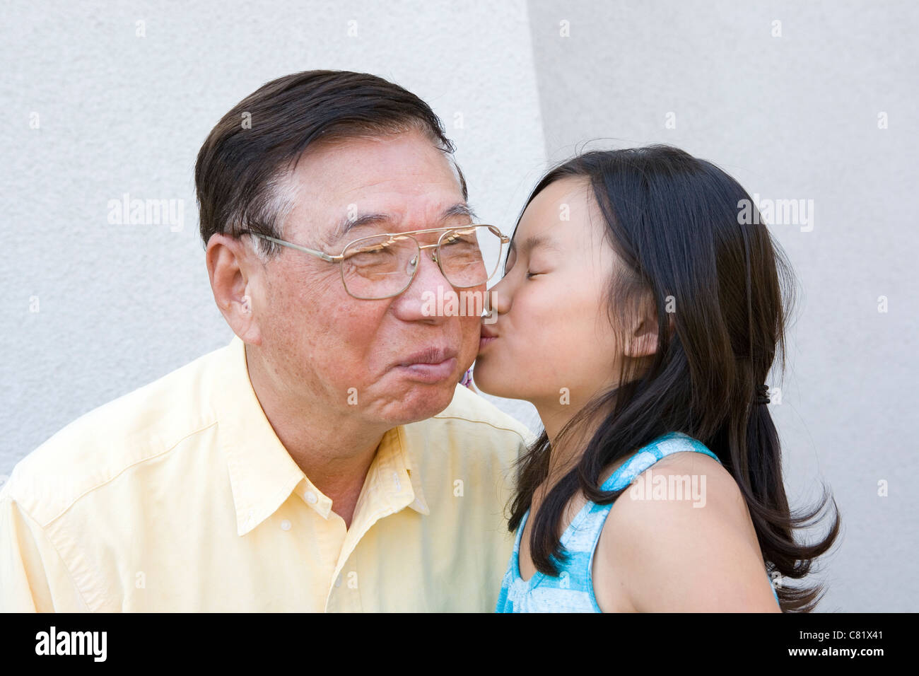 Chinese granddaughter kissing grandfather Stock Photo
