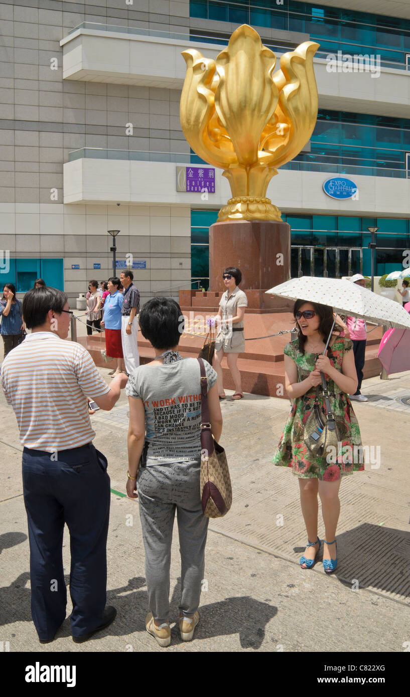 Tourists pose for photos at Golden Bauhinia Square next to the Hong Kong Convention and Exhibition Centre in Wan Chai Stock Photo