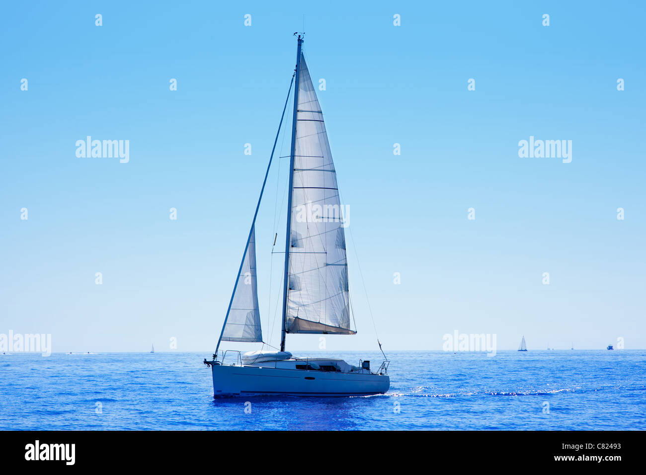 blue sailboat sailing mediterranean sea with water horizon Stock Photo