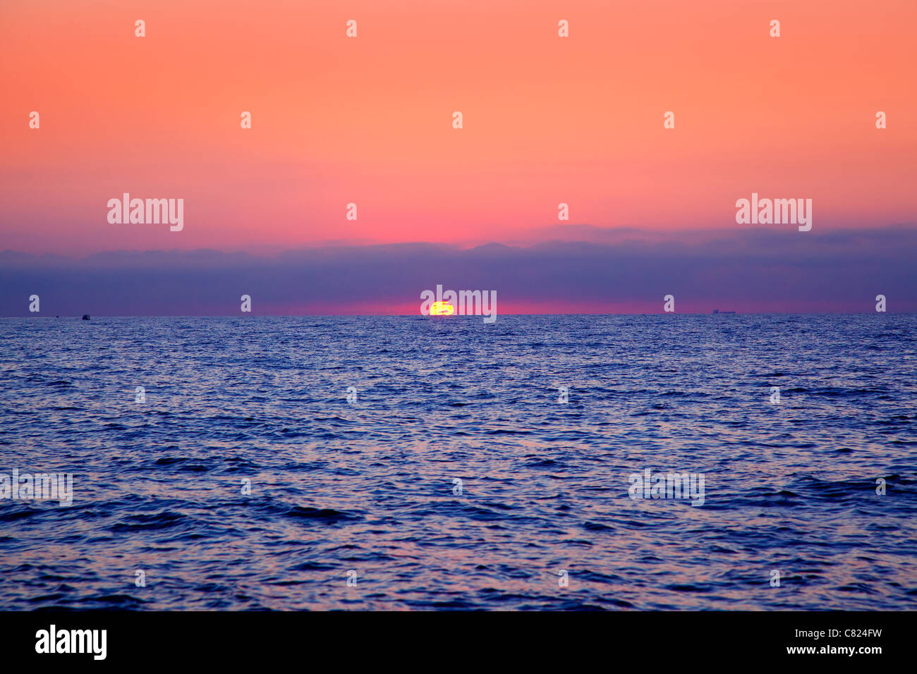 blue sea sunrise with sun in horizon and red sky Stock Photo
