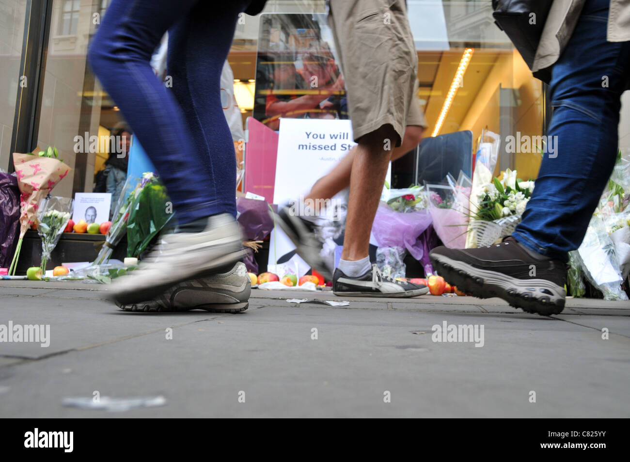 Steve Jobs death memorial shrine Apple Store flowers apples and cards outside the Regent Street store London 7th October 2011 people walking past Stock Photo