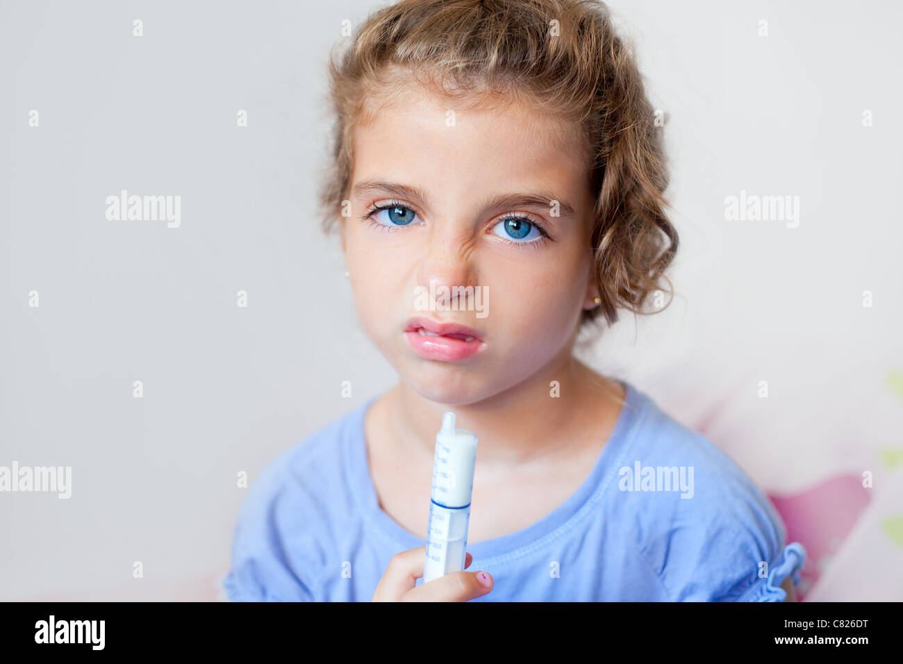 Unhappy kid girl with syringe medicine dose funny expression Stock Photo
