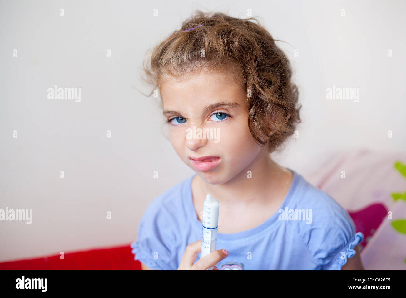 Unhappy kid girl with syringe medicine dose funny expression Stock Photo