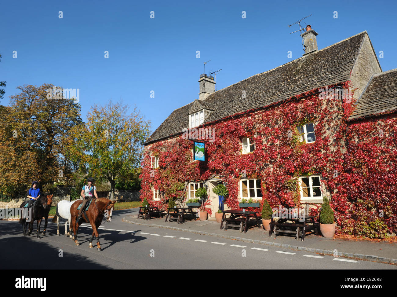 Horse riders passing the Swan in the Gloucestershire village of
