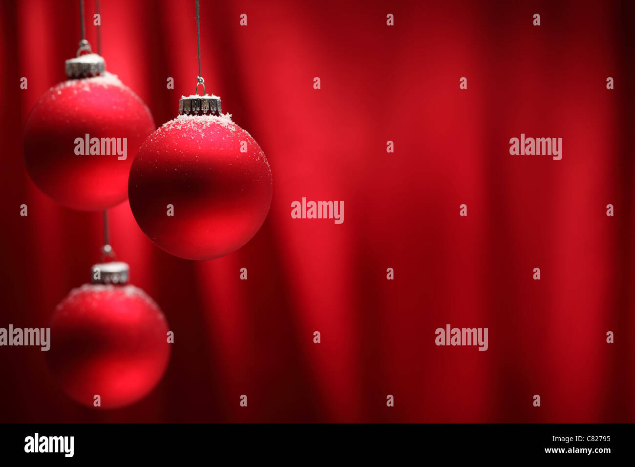 Red Christmas balls hanging over red background. Stock Photo