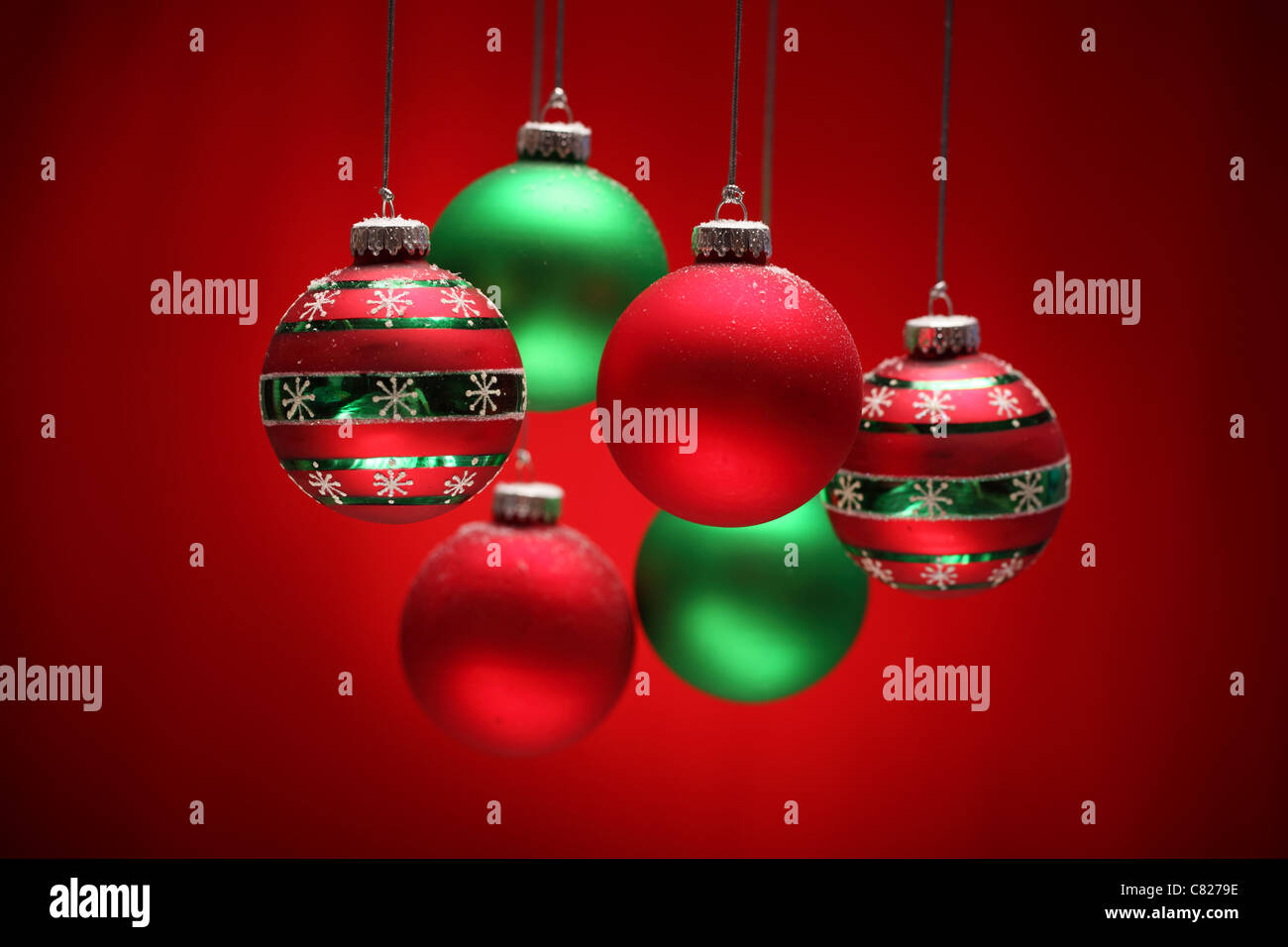 Group of red and green Christmas balls hanging over red background. Stock Photo