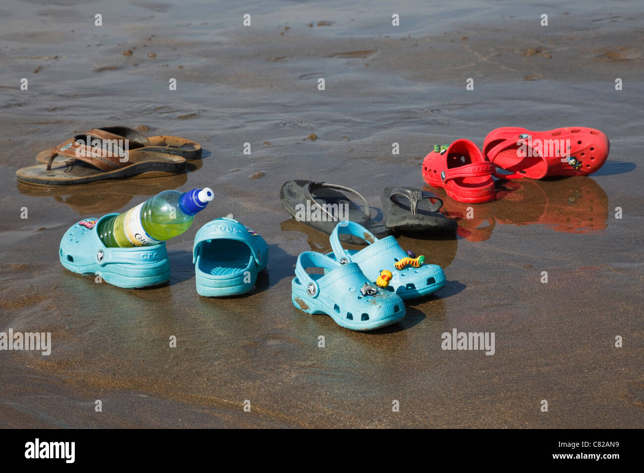 Drink bottle, sandals and plastic Crocs shoes abandoned on a wet sandy  beach by a family with 3 children in summer. England, UK, Britain Stock  Photo - Alamy