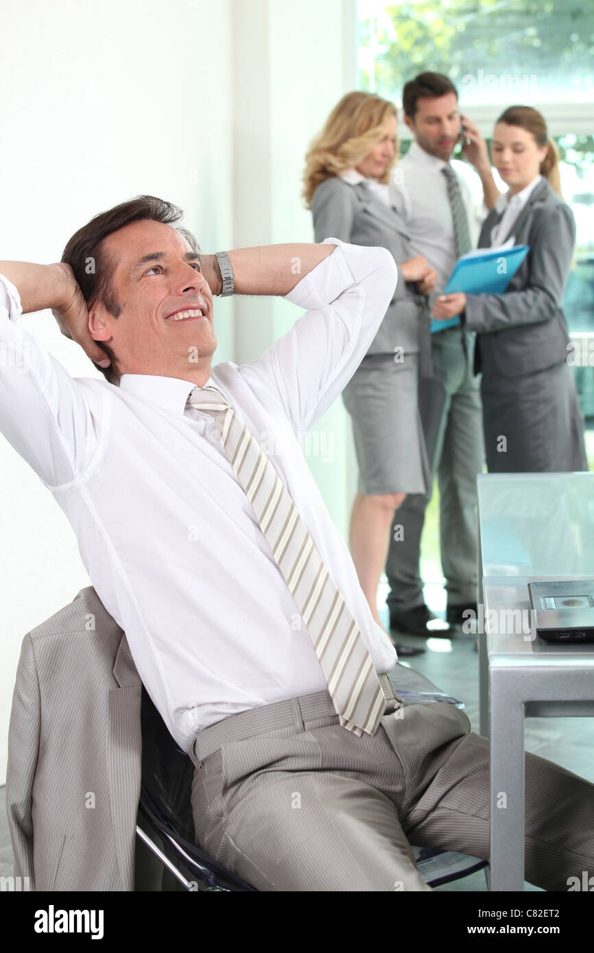 Businessman leaning back in chair with hands on head Stock Photo Alamy