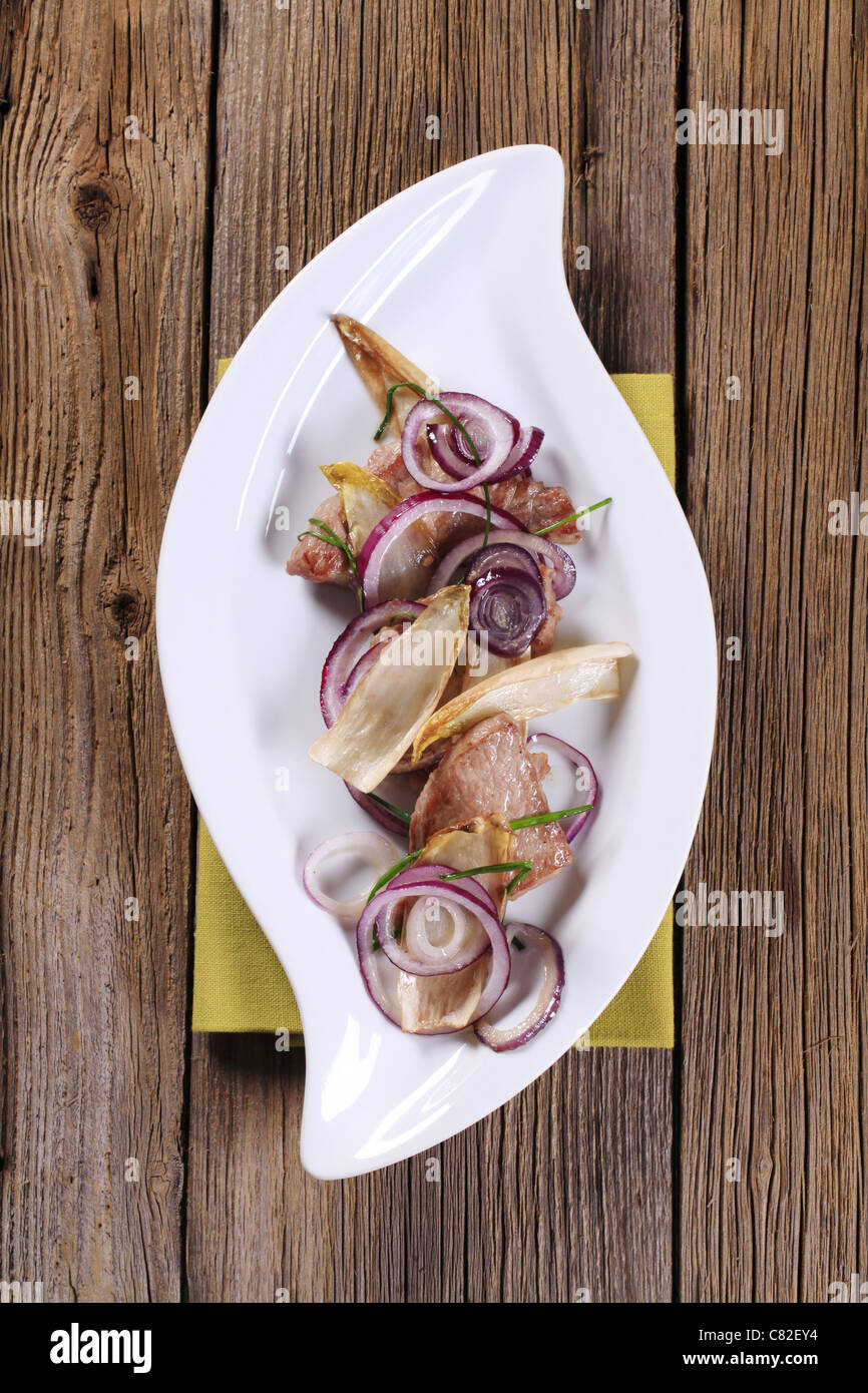 Pan fried meat with onion and endive leaves Stock Photo