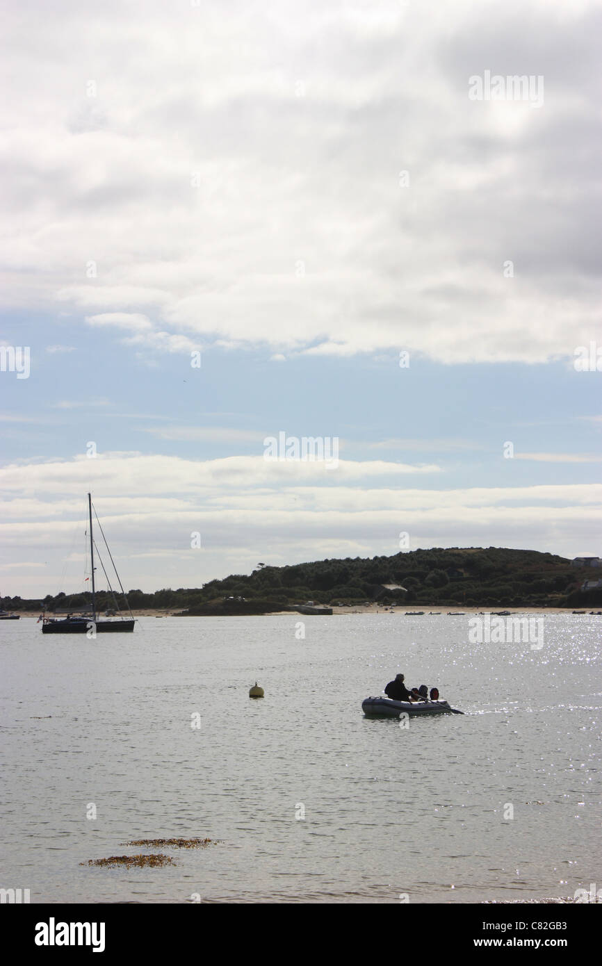 small dingy coming from a yatch in the channel between bryher and tresco Stock Photo