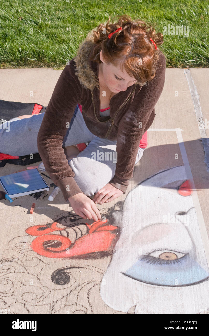 A teen sidewalk chalk artist creates a fanciful image at the Chalk Art