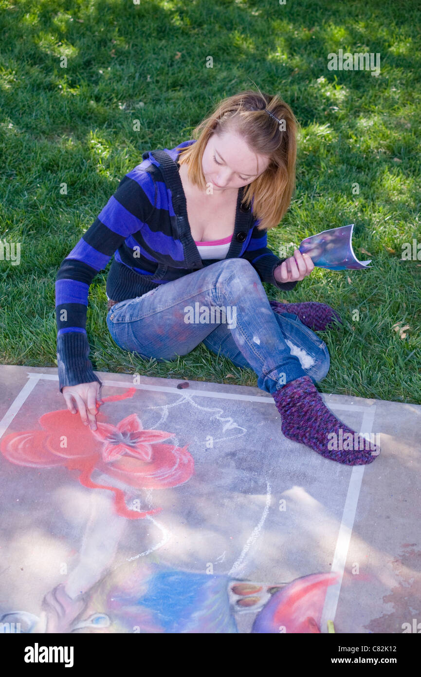 A teen sidewalk chalk artist creates a fanciful image at the Chalk Art