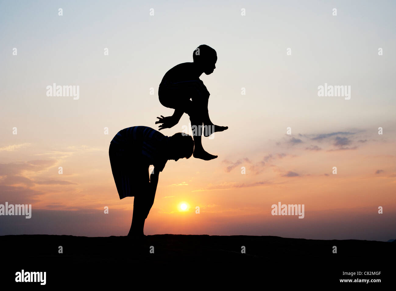 Silhouette of young Indian boys playing leap frog against at sunset. India Stock Photo