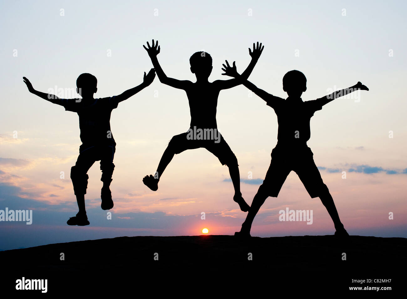 Silhouette of young Indian boys jumping against at sunset. India Stock Photo