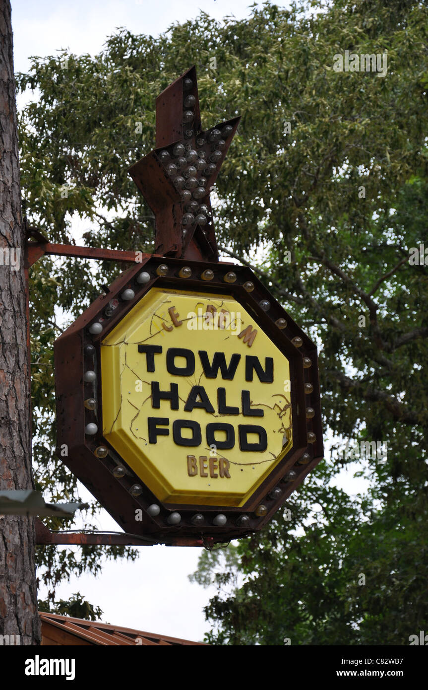 A yellow old outdoor sign mounted to a tree reads Town Hall Food Stock Photo