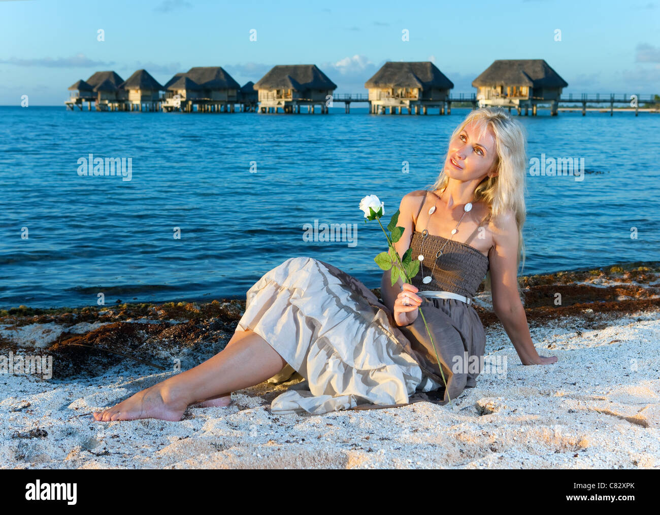 The young woman in a long sundress on a tropical beach. Stock Photo