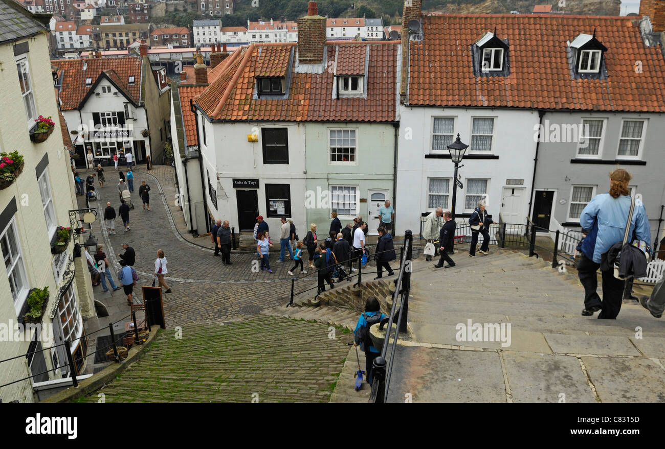 People making their way down the stone steps from the church into the narrow cobbled streets of old Whitby in Yorkshire, England Stock Photo