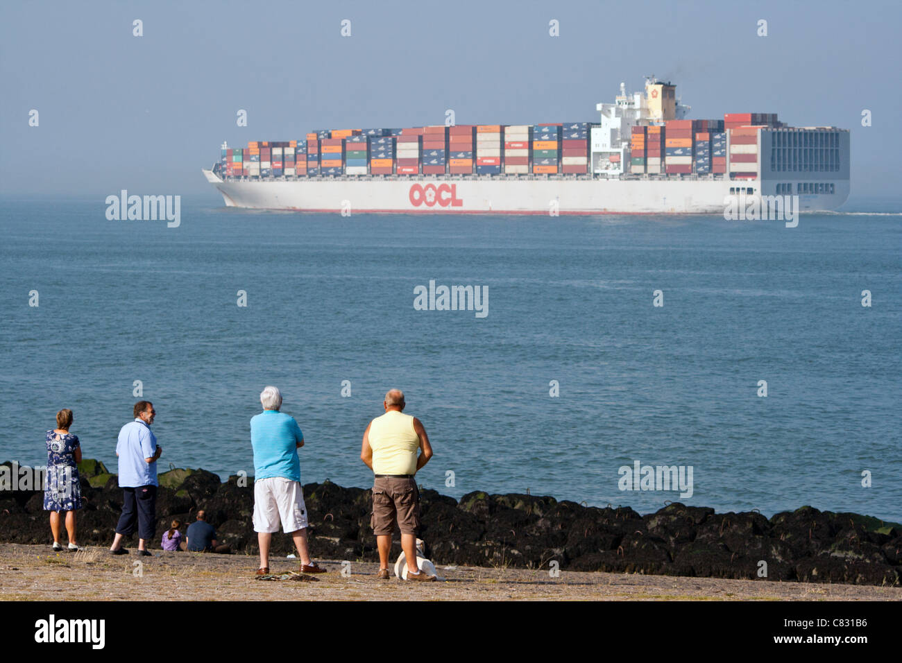 People watching a container ship leaving the port of Rotterdam, The Netherlands Stock Photo