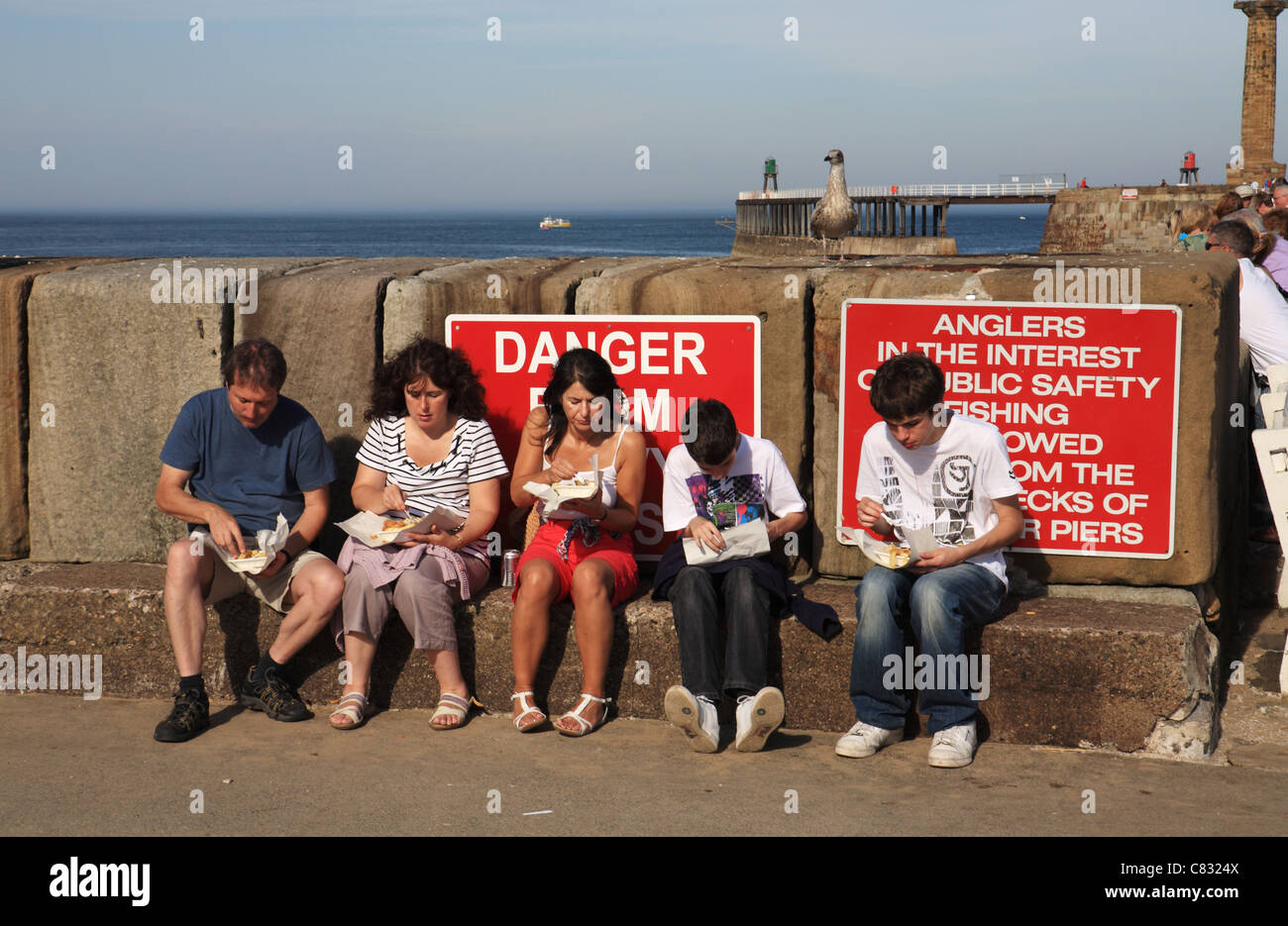 Family eating fish and chips on Whitby pier Stock Photo