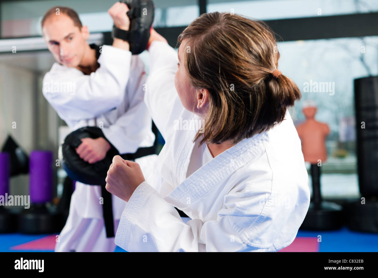 People in a gym in martial arts training exercising Taekwondo, both