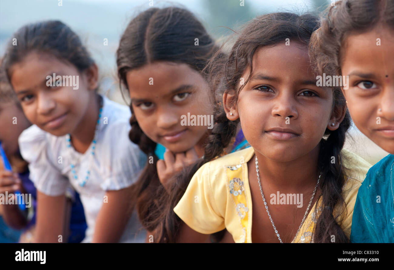 Happy young rural Indian village girls sitting on a wall. Andhra ...