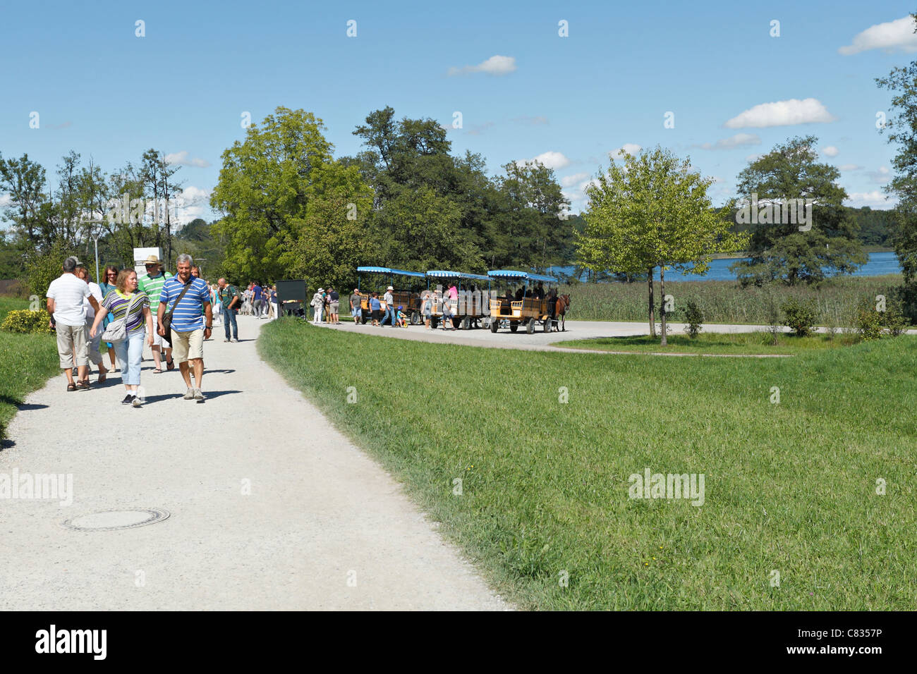 Tourists on a pathway with Horse carriages on the Herreninsel, Chiemgau Upper Bavaria Germany Stock Photo