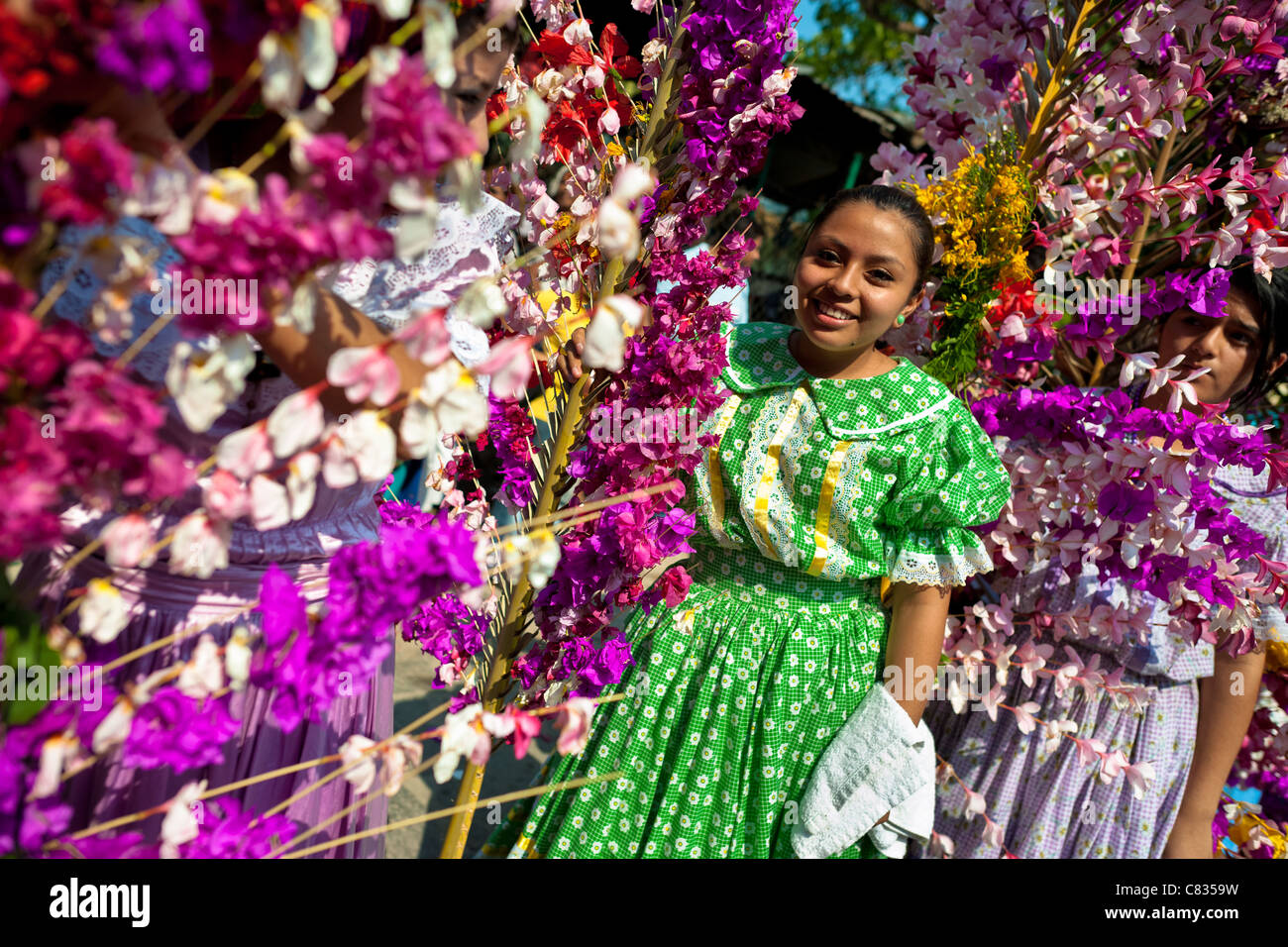 Salvadoran girls carry palm branches with colorful flower blooms during the Flower & Palm Festival in El Salvador. Stock Photo