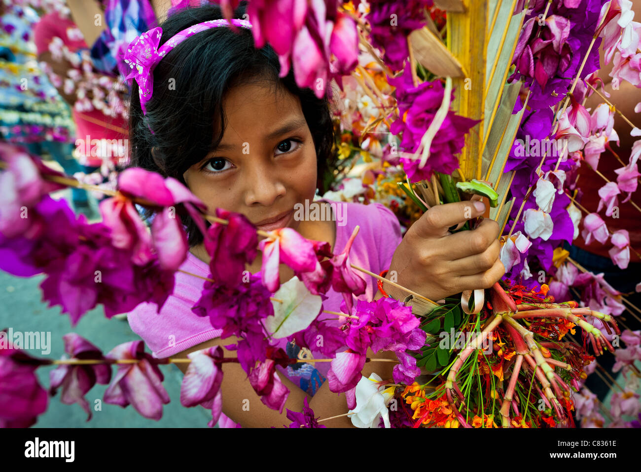 A Salvadoran girl carries a palm branch with colorful flower blooms during the Flower & Palm Festival in El Salvador. Stock Photo
