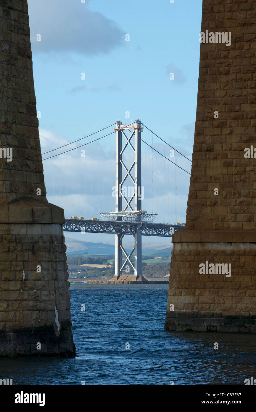 The Forth Road Bridge spanning the Forth Estuary in Scotland seen between the stone supports of the Forth Rail Bridge Stock Photo
