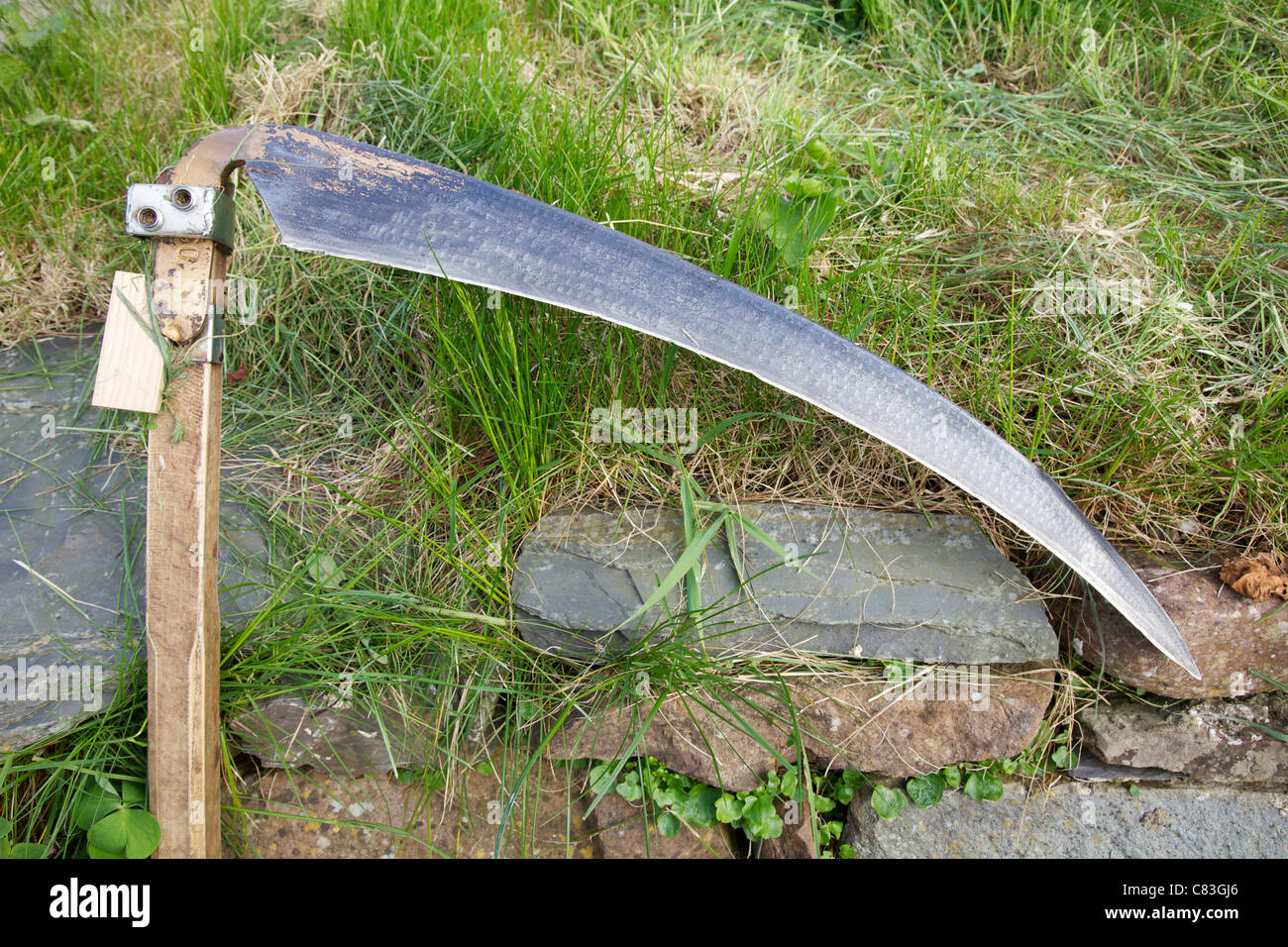 Scythe blade showing wedge used to change the angle of the blade Stock Photo