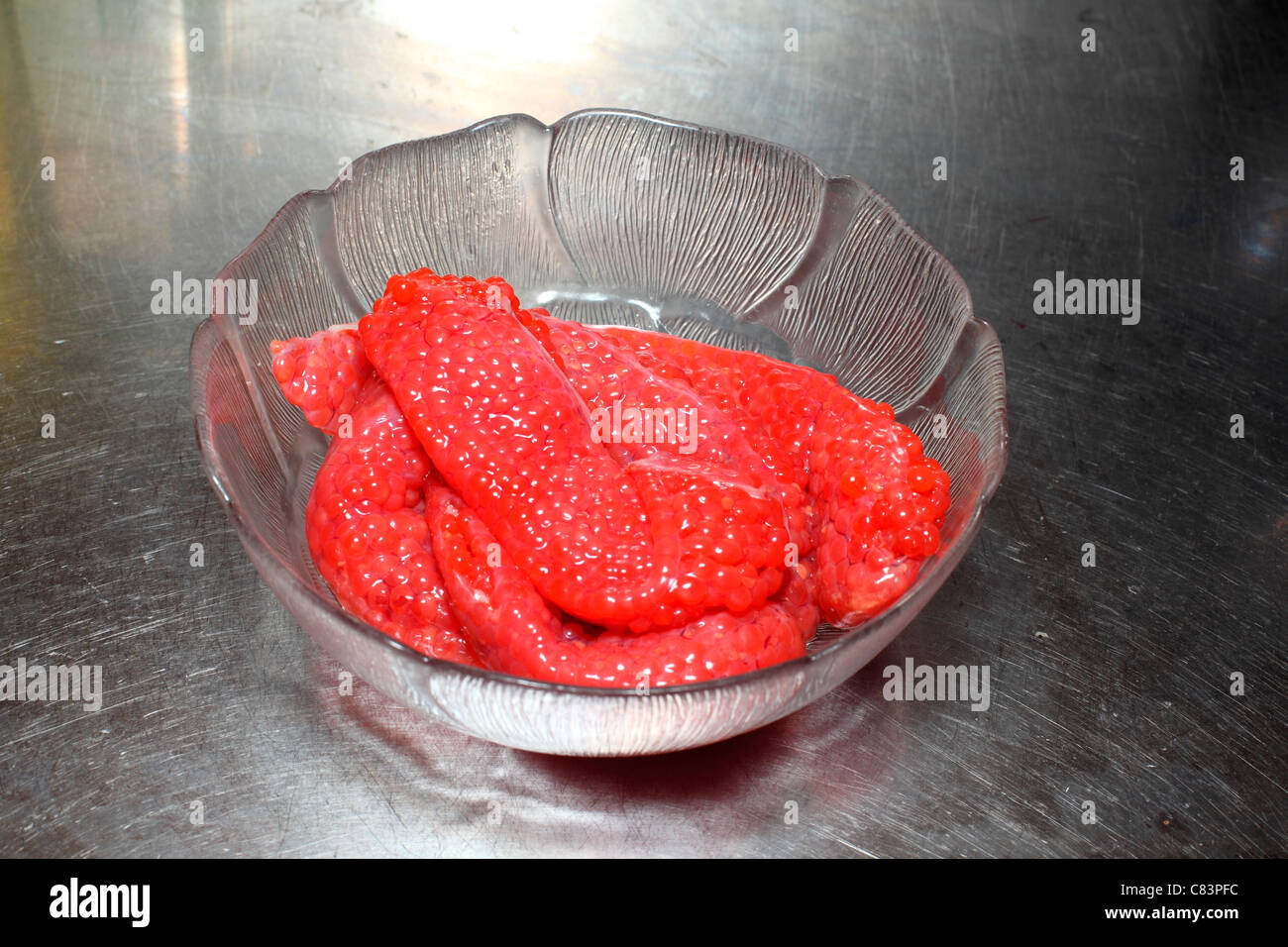 Salmon roe in a  glass bowl on a stainless steel counter Stock Photo