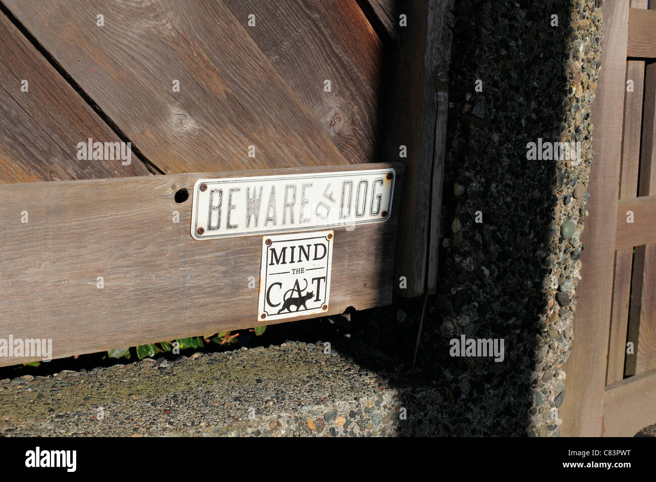Beware of dog and mind the cat sign on a wooden fence Stock Photo