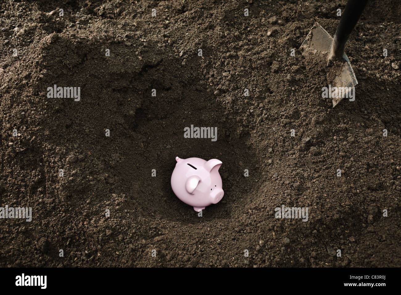 Shovel digging up piggy bank Stock Photo