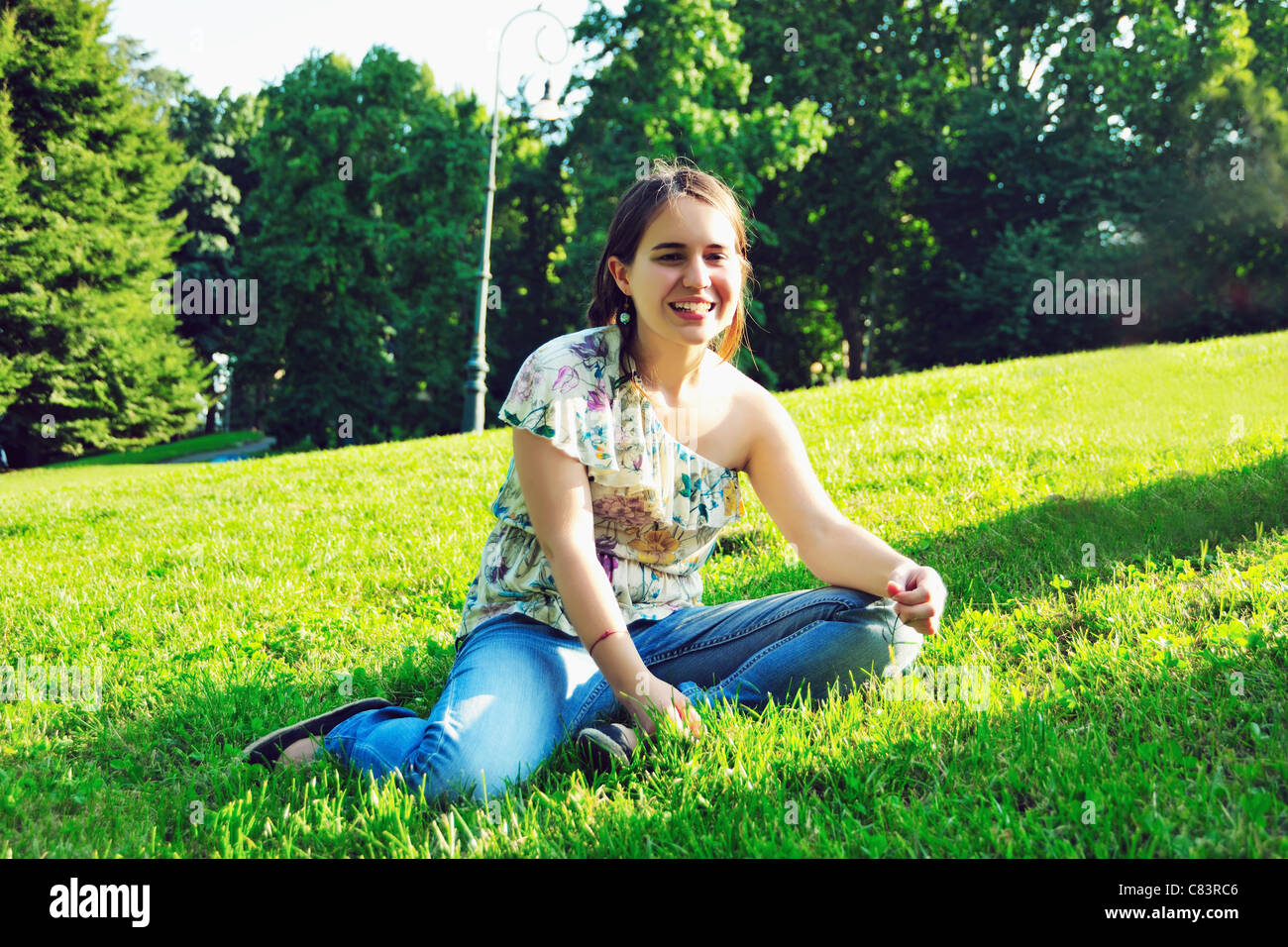 Woman sitting in grass in park Stock Photo - Alamy