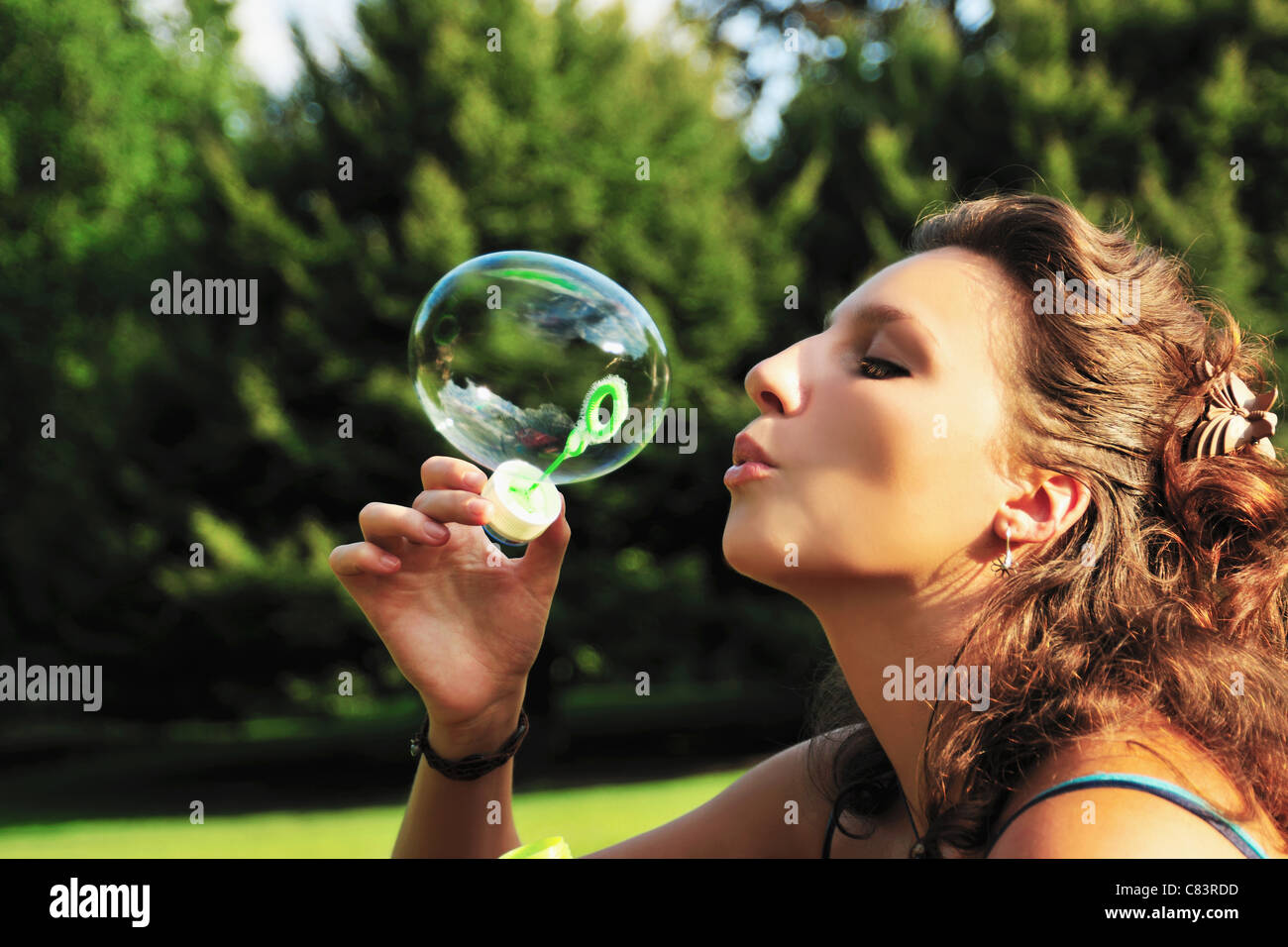 Woman blowing bubbles in park Stock Photo