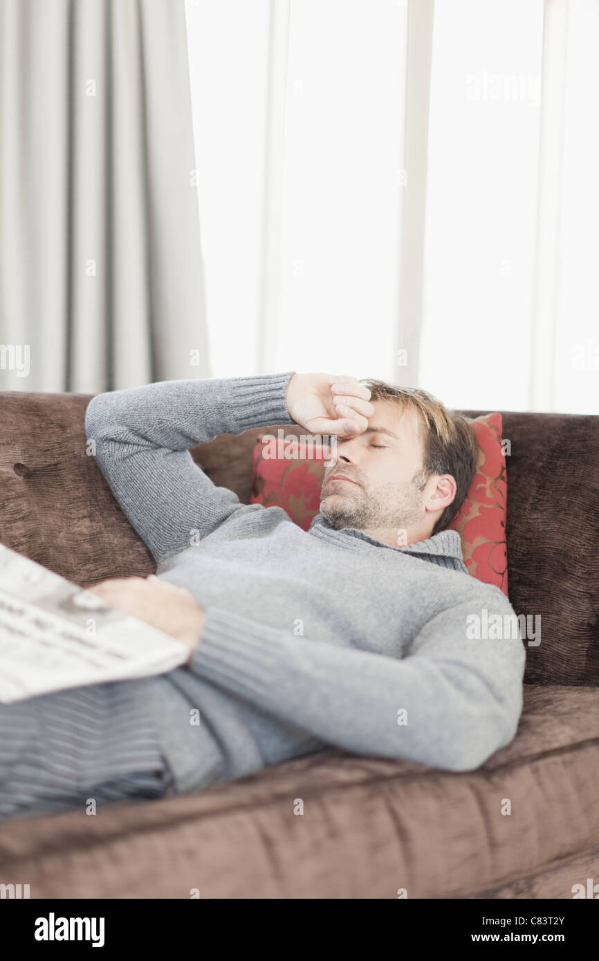 Man with headache resting on couch Stock Photo