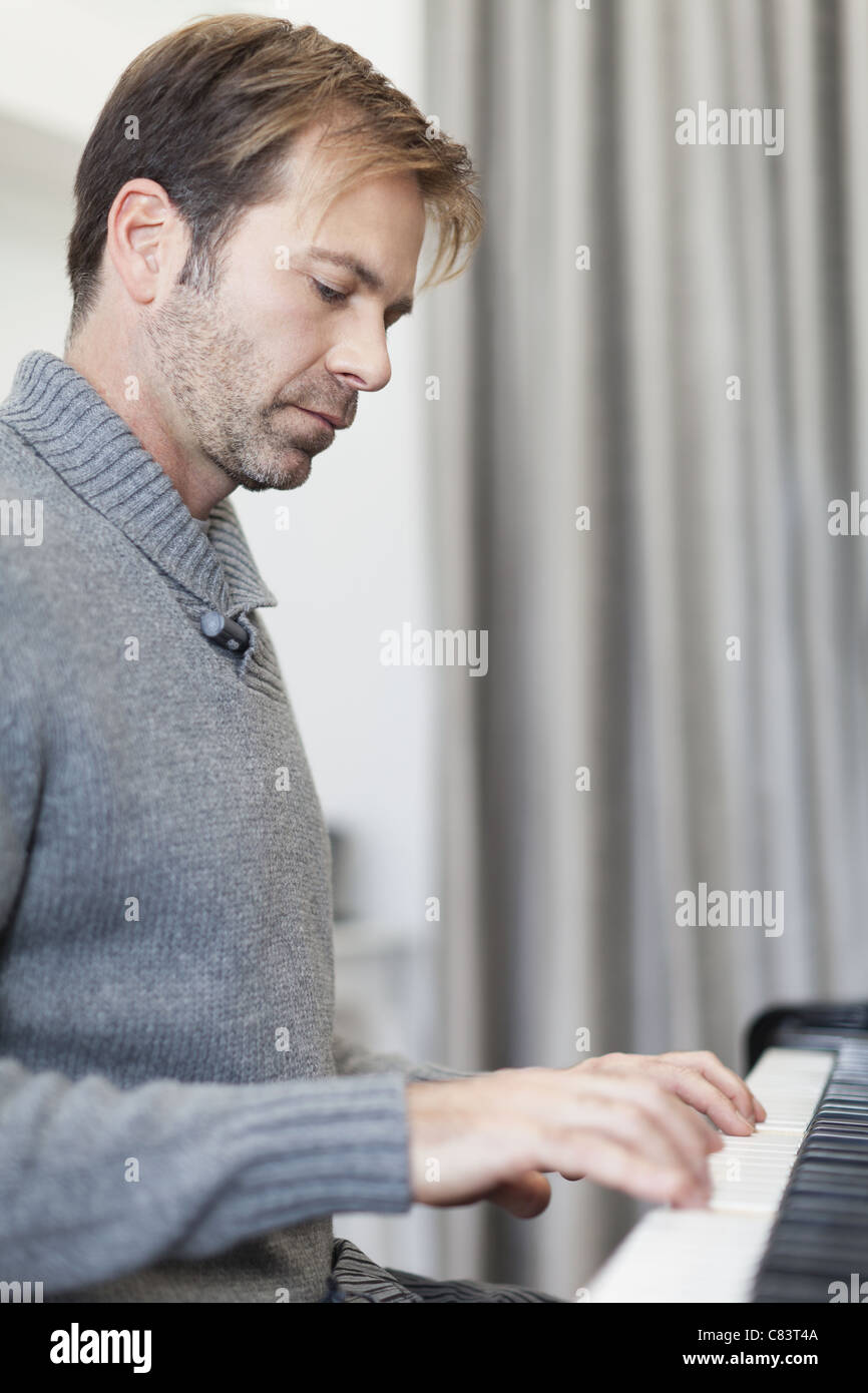 Man playing piano in living room Stock Photo
