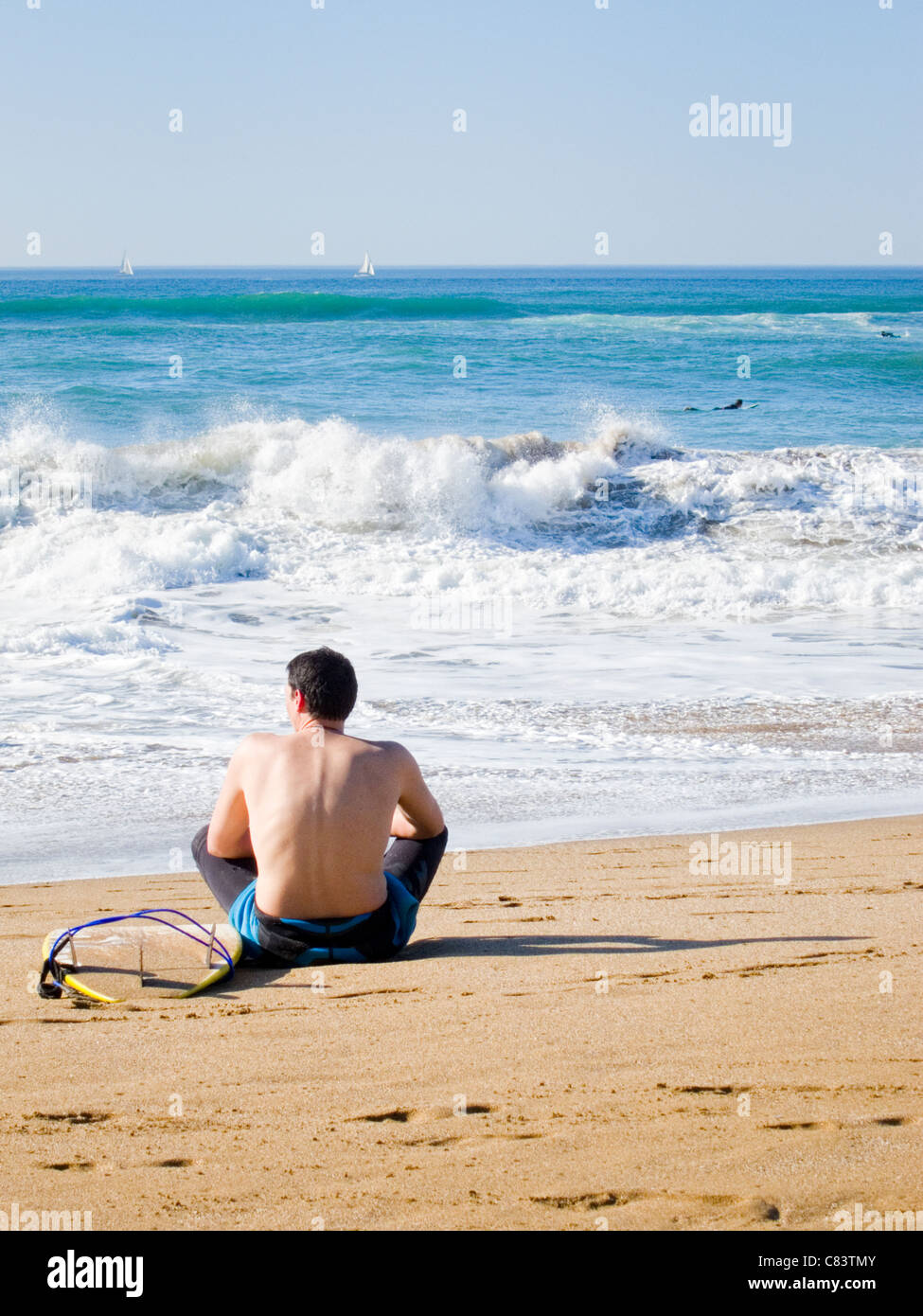 Teenager waiting for surfing sitting in the sand Stock Photo