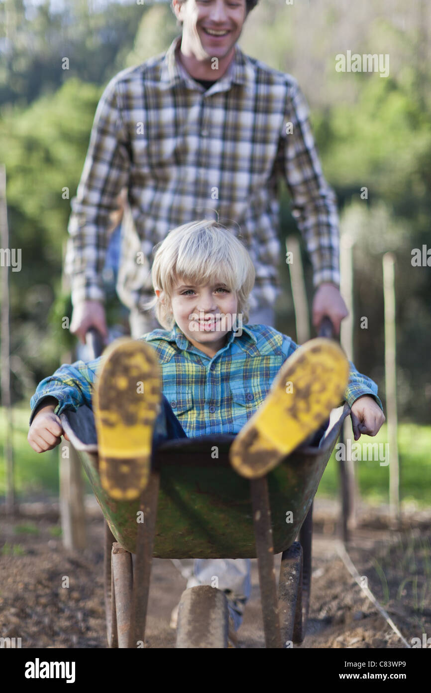 Father pushing son in wheelbarrow Stock Photo