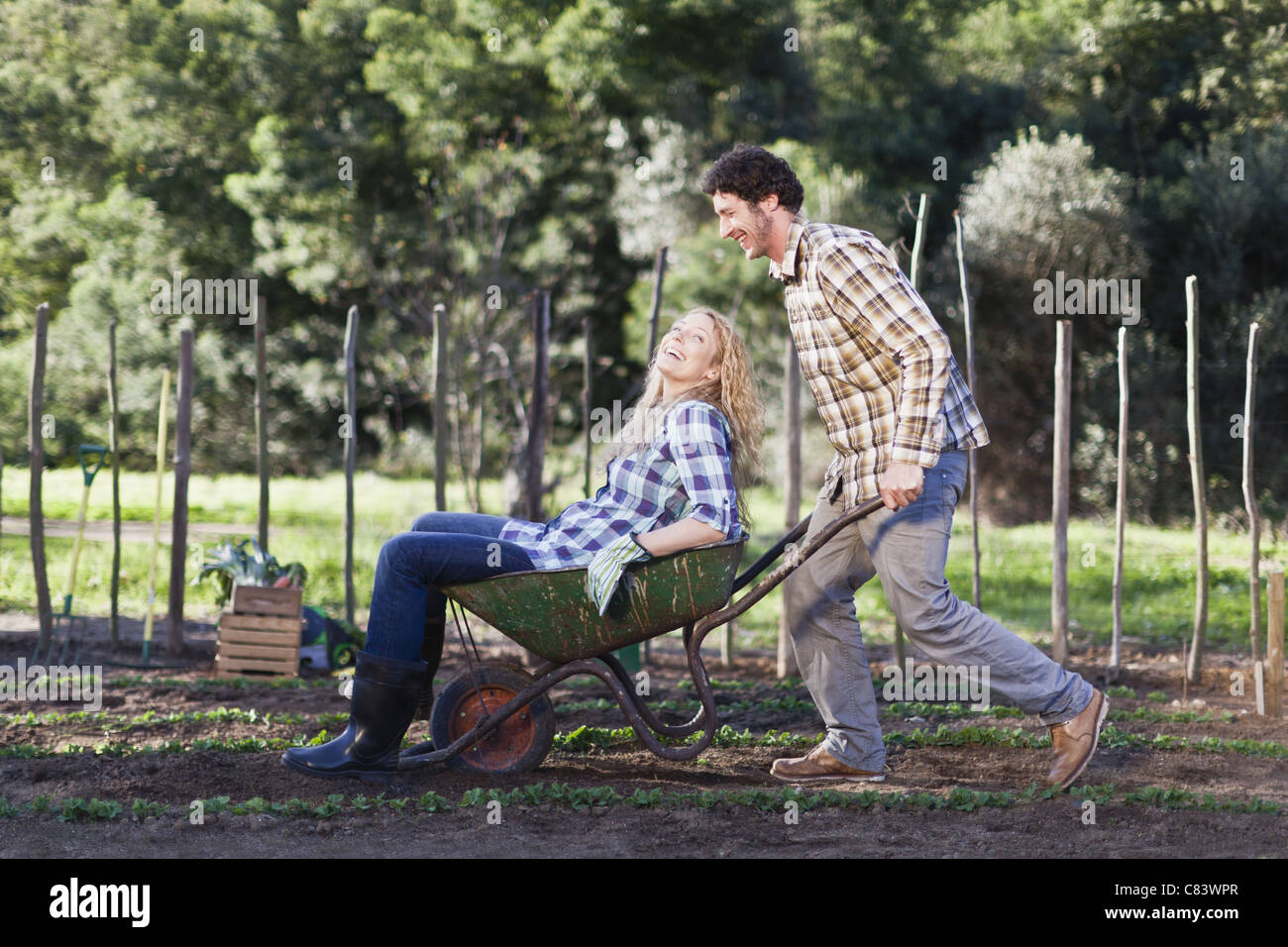 Man pushing girlfriend in wheelbarrow Stock Photo