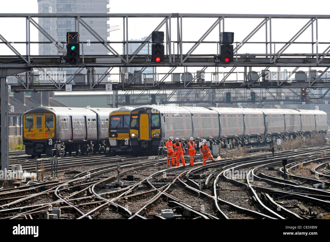 Group of railway workers on electrified track with trains arriving and